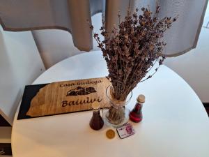 une table avec un vase, des fleurs séchées et des bouteilles dans l'établissement Casa Giubega, à Buşteni