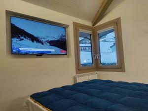 1 dormitorio con 1 cama y TV de pantalla plana en TANA DELLA MARMOTTA - renovated, ski in ski out, turkish bath, garage, storage, en Breuil-Cervinia