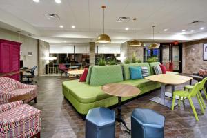 a lobby with a green couch and tables and chairs at Home2 Suites By Hilton Frankfort in Frankfort