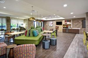 a lobby with a green couch and tables and chairs at Home2 Suites By Hilton Frankfort in Frankfort