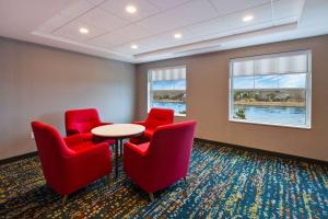 a waiting room with red chairs and a table at Hampton Inn Cape Cod Canal in Buzzards Bay