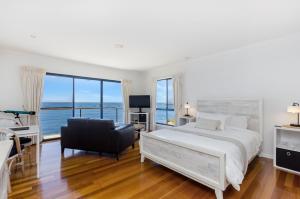 um quarto branco com uma cama e uma cadeira em Clifftop Apartments Portland Vic em Portland