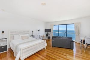 ein weißes Schlafzimmer mit einem Bett und einem Sofa in der Unterkunft Clifftop Apartments Portland Vic in Portland