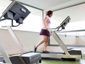 Una donna che cammina su un tapis roulant in palestra di ibis Styles Troyes Centre a Troyes