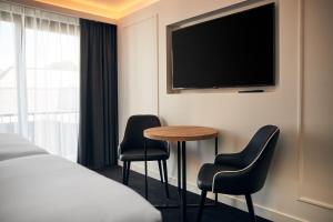 um quarto de hotel com uma mesa e duas cadeiras e uma televisão em Gr8 Hotel Breda em Breda