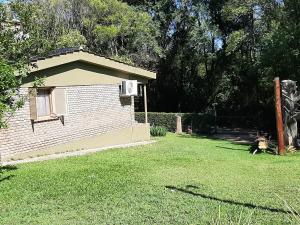 un petit bâtiment en briques dans une cour avec une pelouse dans l'établissement Sierras Chicas La Granja, à Córdoba