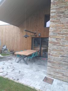 un patio con mesa de madera y sillas en Gîte Le Framboisier V de la distillerie Bio Spirit Belgium, en Neufchâteau