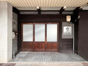 eine Tür zu einem Gebäude mit einem Schild darauf in der Unterkunft Hostel Miyagawa by Murasaki in Takayama