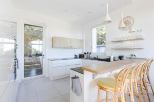 a kitchen with white cabinets and a counter with stools at Villa Élégante Nice avec Vue Mer in Nice