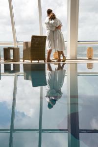 Eine Frau steht in einem Raum mit einer Reflexion im Wasser. in der Unterkunft Wyn. Strandhotel Sylt in Westerland