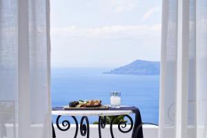 een bord eten op een tafel in een kamer met de oceaan bij San Antonio - Small Luxury Hotels of the World in Imerovígli