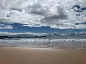 una playa con un cielo nublado y el océano en Terrigal Coastal Casa, en Wamberal