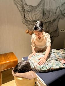 a woman is sitting on a bed with a bag at Citadines Sudirman Jakarta in Jakarta