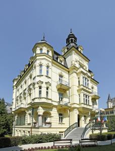 ein großes gelbes Gebäude mit einer Treppe davor in der Unterkunft Hotel Mignon in Karlsbad