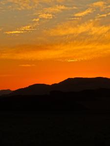 a sunset over the desert with mountains in the background at Wadi rum view camp in Wadi Rum