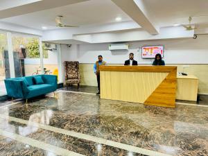 three people standing at a reception desk in a room at ZEN Suites - Golf Course Road Gurgaon in Gurgaon