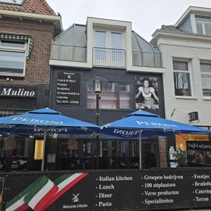 twee blauwe paraplu's voor een gebouw bij Il Mulino House A in Lisse