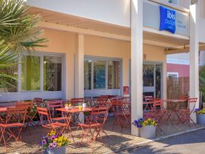 un restaurant avec des tables et des chaises en face d'un bâtiment dans l'établissement Ibis Budget Fréjus Capitou, à Fréjus