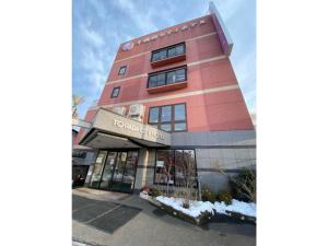 un edificio rosa alto con un cartel. en Towada City Hotel - Vacation STAY 85224v, en Towada