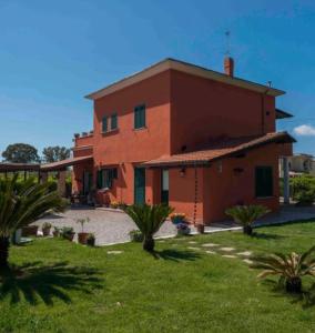 een groot rood gebouw met een tuin met palmbomen bij La locanda di Andrea il pescatore in Borgo Montenero