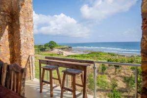 a table and two stools on a balcony overlooking the ocean at Kumekucha Ocean View in Dar es Salaam