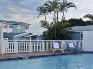 a swimming pool with two chairs next to a house at Premier Splendid Inn Bayshore in Richards Bay