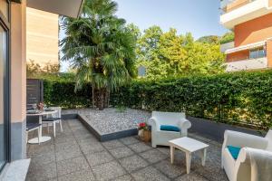 een patio met stoelen en tafels en een palmboom bij Lake Modern Suites - Free Parking in Lugano