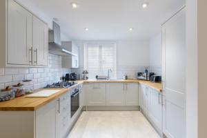 een keuken met witte kasten en houten aanrechtbladen bij Luxury 5 Bedroom House By The Sea in Brighton & Hove