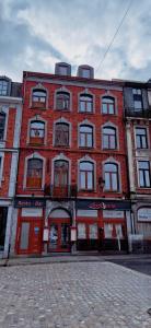 a large brick building with red doors on a street at NOMAD APARTMENTS - Astrid in Dinant