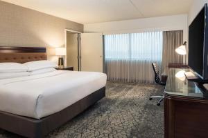 um quarto de hotel com uma cama, uma secretária e uma televisão em Sheraton Detroit Metro Airport em Romulus