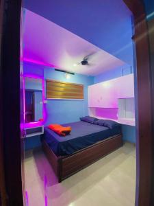 a room with a bed with pink lights on it at VEE CEE TOWER FURNISHED APPARTMENT in Sultan Bathery