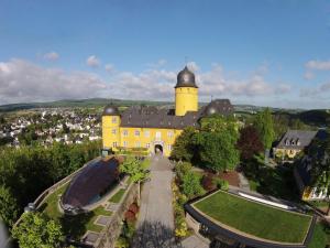 une vue aérienne sur un bâtiment jaune avec une tour dans l'établissement Hotel Schloss Montabaur, à Montabaur