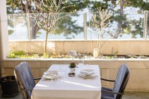 una mesa con un mantel blanco y sillas frente a una ventana en Rogač Rooms & Restaurant, en Omiš