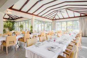 un comedor con mesas y sillas blancas y ventanas en Rogač Rooms & Restaurant, en Omiš