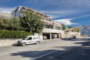 un coche blanco estacionado frente a un edificio en Rogač Rooms & Restaurant, en Omiš