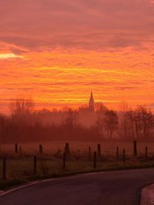 a sunset over a field with a church in the distance at Suite & SPA à La Ferme 1802 in Sainghin-en-Mélantois