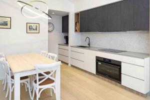 una cucina con tavolo e una cucina con armadietti bianchi di Beach luxury retreat- 2 bedroom, 2 bathroom, shops, pet friendly, parking a Ocean Grove