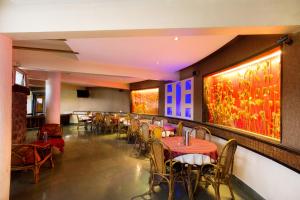 un restaurante con mesas, sillas y pinturas en las paredes en Treebo Premium Niraali Executive, en Pune