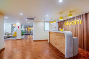 Bloom Hotel - Medicity Gurugram, Near Medanta Hospital في جورجاون: مكتب مع مكتب استقبال وعلامة زهرة على الحائط