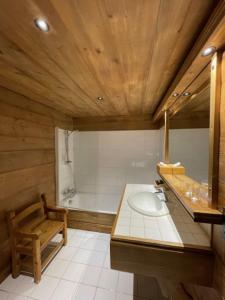 a bathroom with a wooden ceiling and a sink and a tub at Les Chalets de la Serraz in La Clusaz