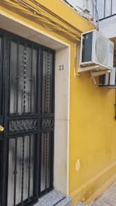 um edifício amarelo com janela e ar condicionado em Disfruta de un barrio tranquilo em Alcalá de Guadaira