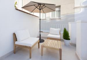 a patio with two chairs and a table and an umbrella at Divino Hotel Boutique in Sitges