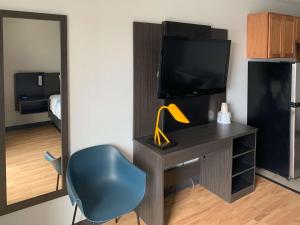 Cette chambre comprend un bureau avec une télévision et une chaise. dans l'établissement Studio 6-Lincoln, NE - Airport, à Lincoln