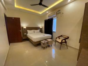 a bedroom with a bed and a chair and a window at Baga Keys by RJ14 in Old Goa