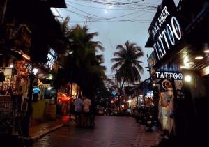 a city street at night with shops and palm trees at Baga Keys by RJ14 in Old Goa