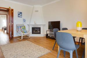 - un salon avec une table, des chaises et une cheminée dans l'établissement Ericeira Beach Apartment, à Ericeira