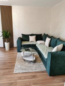 a living room with a green couch and a table at Apartman Bonsai in Subotica