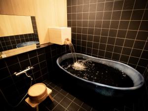 a bathroom with a tub with water coming out of it at Glansit Kyoto Kawaramachi in Kyoto