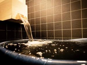 a bath tub filled with water in a bathroom at Glansit Kyoto Kawaramachi in Kyoto