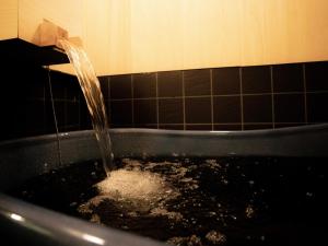 a bath tub filled with water in a bathroom at Glansit Kyoto Kawaramachi in Kyoto